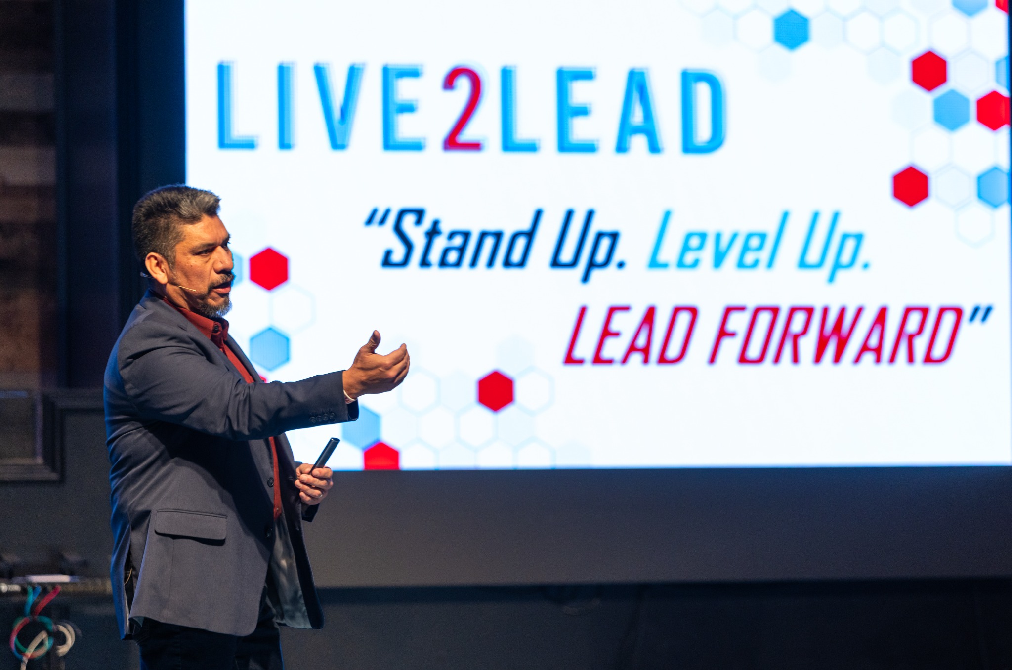 Heber Mena presenting beside the Live2Lead event theme