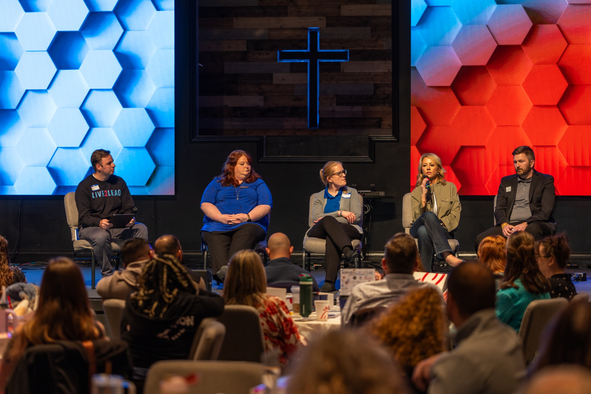 Five panelists in conversation onstage with the audience in the foreground