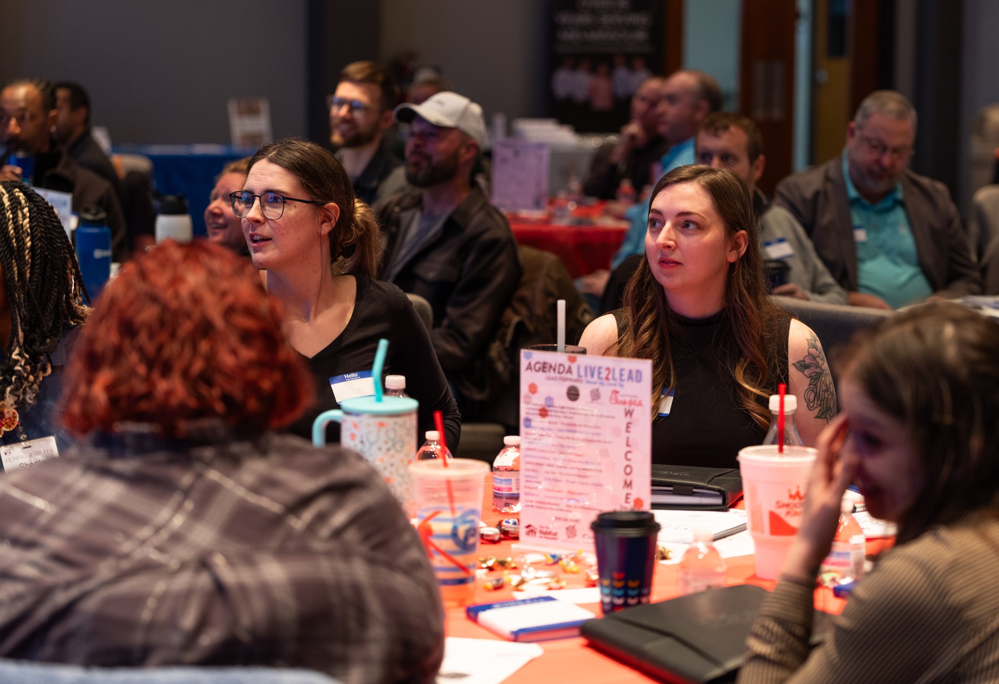 Attendees listening at a table with a Live2Lead agenda