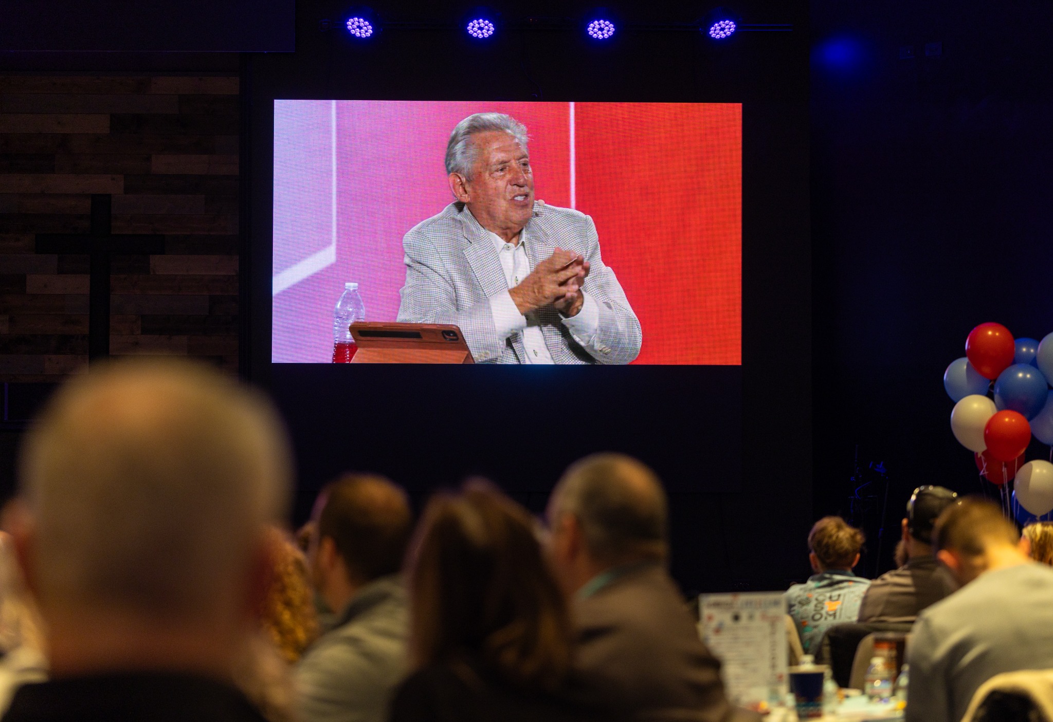 Attendees watching a recorded John C. Maxwell presentation on the event screen